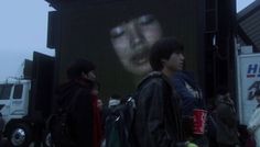 people standing in front of a large screen with a woman's face on it