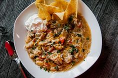 a white plate topped with chicken and tortilla soup next to nachos