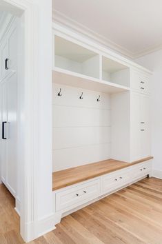 an empty white room with wooden flooring and built - in storage units on the wall