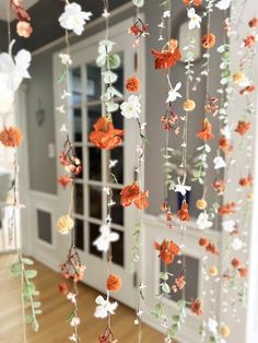 an orange and white flower mobile hanging from the ceiling in front of a doorway with glass doors