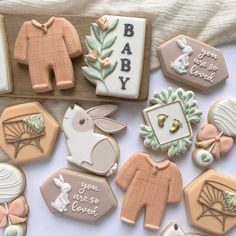 decorated cookies are laid out on a white tablecloth, with baby's names and other decorations