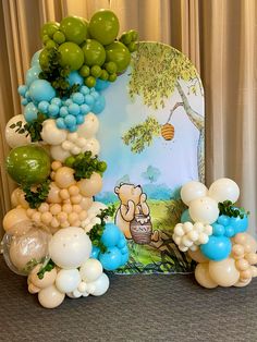 balloon arch with winnie the pooh on it and balloons in blue, white and green