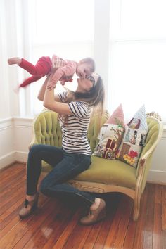 a woman sitting on top of a green couch holding a baby