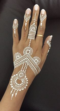 a woman's hand with henna tattoos on it and her hands painted white