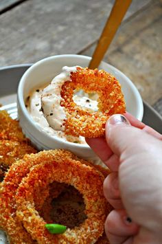 a person dipping something into a bowl with some kind of dip in it on a plate