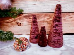 three small trees made out of clay sitting next to a christmas ornament and pine tree