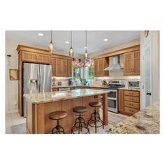 a kitchen with wooden cabinets and marble counter tops