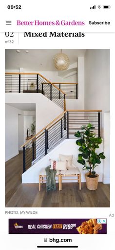 a white couch sitting under a stair case next to a potted plant on top of a wooden floor