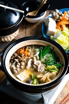 a bowl of soup is sitting on a stove top next to a plate of food