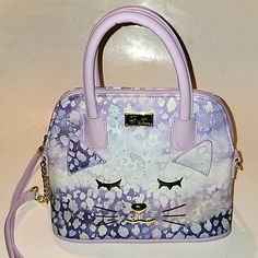 Luv Betsey Lini Satchel With Top Zip Closure. Features Pebbled Faux Leather W/ Cheetah Purple/ Lilac Print - Gold Tone Hardware And Adorable Cat Face - Double Rolled Carry Handles W/ 4” Strap Drop - Chain And Faux Leather Crossbody Strap W/ 22” Drop (Not Adjustable Or Detachable) - Fabric Lined Interior W/ 1 Zipper Pocket And 2 Open Slip Pockets - 10”W X 8”H X 4”D. New Without Tags. From A Smoke-Free And Pet Free Home. Purple Bags With Adjustable Handle For Daily Use, Purple Bag With Adjustable Handle For Daily Use, Daily Use Purple Bag With Adjustable Handle, Trendy Purple Bag With Detachable Handle, Trendy Purple Bags With Detachable Handle, Trendy Purple Top Handle Bag, Purple Rectangular Bags With Adjustable Handle, Purple Crossbody Bag With Zipper Closure, Purple Travel Bag With Adjustable Handle