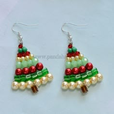 a pair of christmas tree earrings with pearls and beads on them, sitting on a white surface