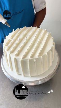 a person cutting into a white cake on top of a metal table with a knife