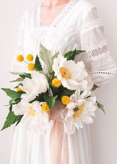 a woman holding a bouquet of white and yellow flowers