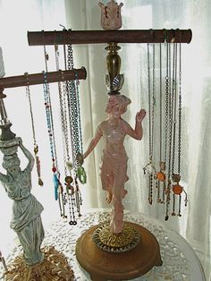 a statue is standing on top of a table with jewelry hanging from it's sides