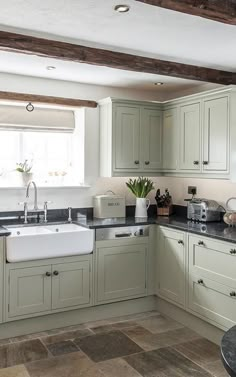 a kitchen filled with lots of green cabinets and counter top space next to a window