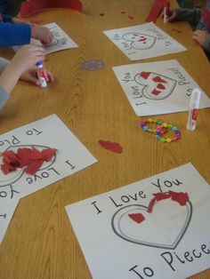 children are sitting at a table making valentine's day cards with crayons