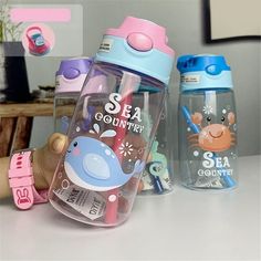 two children's sippy cups with straws in them