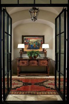 an entry way with a painting on the wall and two lamps hanging from the ceiling