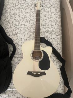 a white guitar sitting on top of a bed