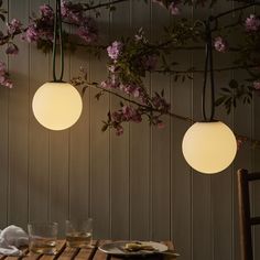 three lights hanging from the ceiling above a table with plates and glasses in front of it