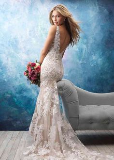 a woman in a wedding dress standing next to a couch and holding a flower bouquet