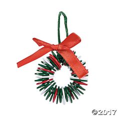 a christmas ornament hanging from a red ribbon with green and red pins attached to it