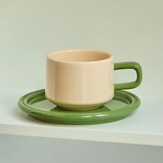 a green and white cup sitting on top of a saucer