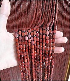 a hand is holding several red beads