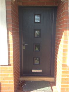 a black front door with three sidelights on brick walls and an entry mat in the foreground