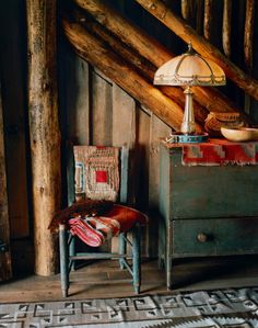 an old chair sitting next to a lamp in a room with wooden walls and beams