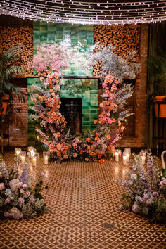 an indoor ceremony with flowers and candles on the floor in front of a fire place