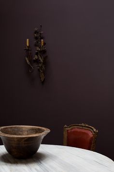 a wooden bowl sitting on top of a white table next to a red leather chair