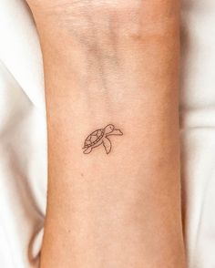 a small tattoo on the wrist of a woman with a turtle in it's shell