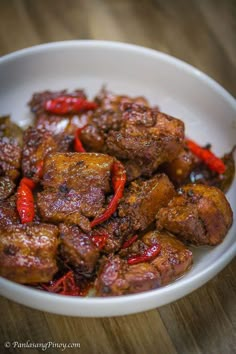 a white bowl filled with meat and peppers