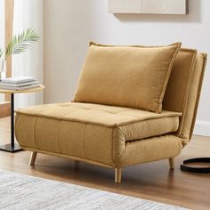 a tan chair sitting on top of a hard wood floor next to a white rug