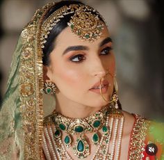 a woman in a bridal outfit with jewelry on her neck and headpieces