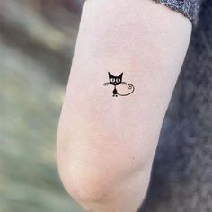 a small black cat tattoo on the ankle