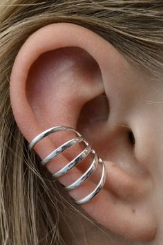 a woman's ear with three silver rings attached to the side of her ear