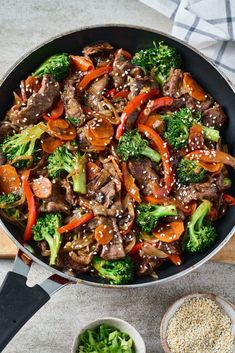 a skillet filled with beef, broccoli and peppers