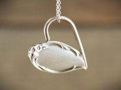 a close up of a silver necklace with a heart shaped object hanging from it's side