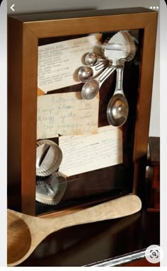 a wooden frame with spoons and notes in it