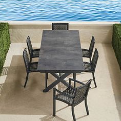 an outdoor dining table and chairs with water in the background