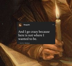 a man holding a lit candle in his hand and reading a book with a quote on it