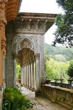 an old building with columns and arches on the outside, surrounded by greenery in the foreground