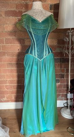 One of a kind mermaid themed corset and skirt set in shimmery shot blue/greens.   The corset is made with a strength layer of Coutil and is boned with a mixture of flat and spiral steel bones, it is back lacing only with an unboned modesty panel.   The corset measures 24" at the waist so would probably best suit natural waists in the region of 27-30"  Fully laced the corset measures   Bust 35"  Waist 24"  Upper hip 34"  Length at front centre 14.5" Green Mermaid Dress With Fitted Bodice, Green Strapless Fitted Mermaid Dress, Green Fitted Bodice Corset For Party, Blue Overbust Corset Dress For Costume Party, Blue Fitted Corset Dress For Costume, Fitted Fantasy Skirt For Costume Party, Green Sleeveless Corset Dress With Boned Bodice, Blue Underbust Corset Dress For Party, Fitted Fantasy Corset Dress For Fancy Dress