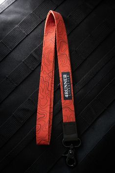 an orange lanyard strap with black buckles on the back of a car seat