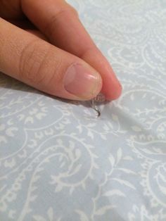 a person's hand with a tiny ring on top of a blue and white fabric