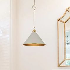 a bathroom with a sink and mirror hanging from it's ceiling, in front of a gold framed mirror