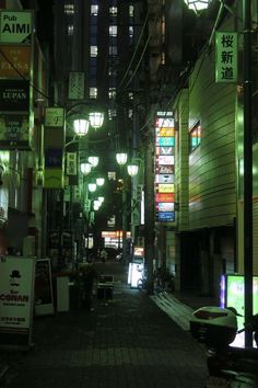 an alley way with lots of signs and lights on the buildings in the background at night