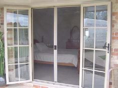 an open patio door leading to a bedroom with a bed in the window and another room behind it